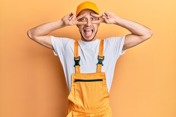 Young hispanic man wearing handyman uniform amazed and smiling to the camera while presenting with hand and pointing with finger.