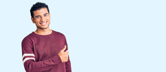 Hispanic handsome young man wearing casual clothes doing happy thumbs up gesture with hand. approving expression looking at the camera showing success.