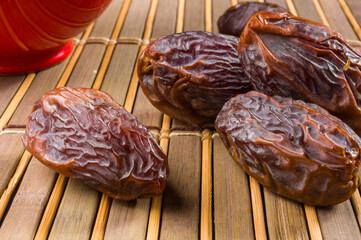 Big luxury dried date fruit on the bamboo mat, kurma ramadan kareem concept, close up.