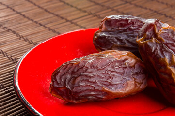 Big luxury dried date fruit in bowls on the bamboo mat, kurma ramadan kareem concept, close up.