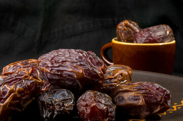 Big luxury dried date fruit in bowls on the dark surface, kurma ramadan kareem concept, close up.