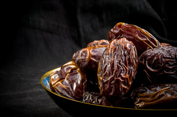Big luxury dried date fruit in bowls on the dark surface, kurma ramadan kareem concept, close up.
