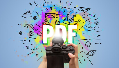 Close-up of a hand holding digital camera with abstract drawing and PDF inscription