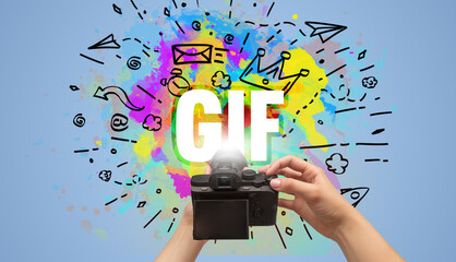 Close-up of a hand holding digital camera with abstract drawing and GIF inscription