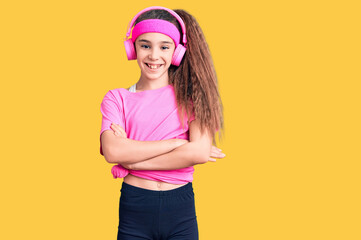 Obraz na płótnie Canvas Cute hispanic child girl wearing gym clothes and using headphones happy face smiling with crossed arms looking at the camera. positive person.