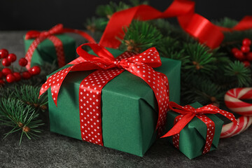 Green Christmas gift boxes with red bows on grey table