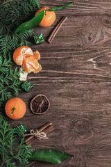 Composition with tangerines, cinnamon sticks and spruce branches on a dark wooden background. Top view, copy space. 