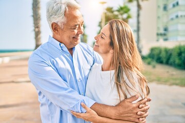 Middle age hispanic couple smiling happy hugging at the promenade.