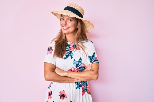 Middle age hispanic woman wearing summer hat happy face smiling with crossed arms looking at the camera. positive person.