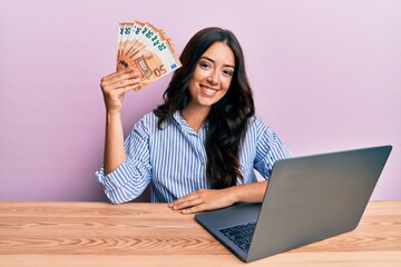 Beautiful brunette young woman working at the office holding euros looking positive and happy...