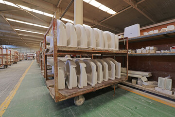 Obraz na płótnie Canvas Semi-finished ceramic toilets are on shelves in a factory, China