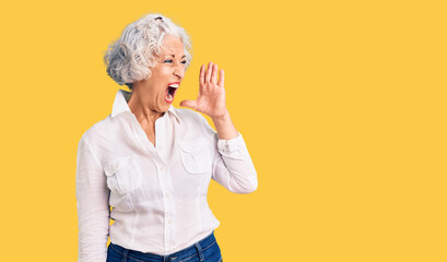 Senior grey-haired woman wearing casual clothes shouting and screaming loud to side with hand on mouth. communication concept.