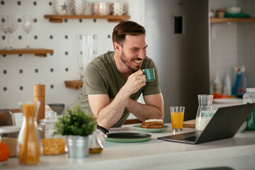 Fototapeta na wymiar Young man eating breakfast and reading the news online. Handsome man enjoying at home..