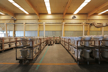 Semi-finished ceramic toilets are on shelves in a factory, China