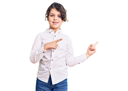 Cute hispanic child wearing casual clothes smiling and looking at the camera pointing with two hands and fingers to the side.