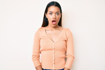 Young beautiful latin girl wearing casual clothes scared and amazed with open mouth for surprise,...
