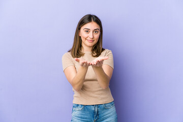 Fototapeta premium Young caucasian woman holding something with palms, offering to camera.