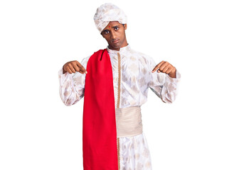 African handsome man wearing tradition sherwani saree clothes pointing down looking sad and upset, indicating direction with fingers, unhappy and depressed.