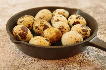 Quail eggs in a cast iron skillet on a table. Close up view