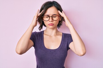 Young beautiful woman wearing casual clothes and glasses suffering from headache desperate and stressed because pain and migraine. hands on head.