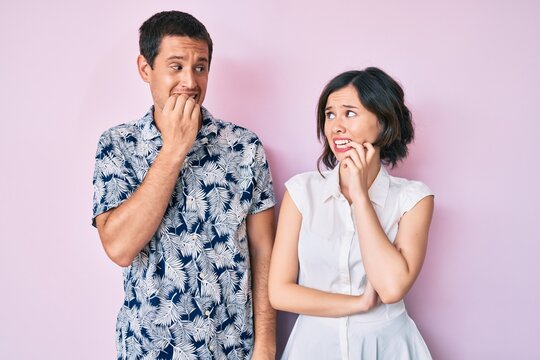 Beautiful couple wearing casual clothes looking stressed and nervous with hands on mouth biting nails. anxiety problem.
