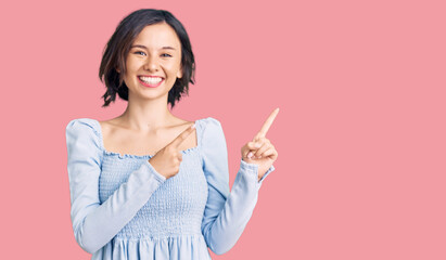 Young beautiful girl wearing casual clothes smiling and looking at the camera pointing with two hands and fingers to the side.