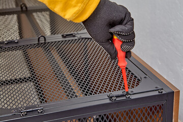 Fototapeta premium Handyman is screwing furniture door hinges while assembling modern shelf.