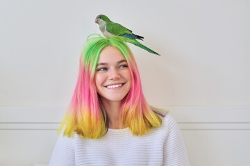 Trendy fashionable with colored hairstyle teenager with green parrot on head © Valerii Honcharuk