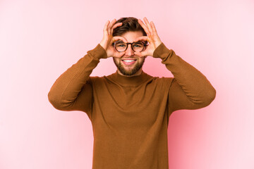 Fototapeta premium Young caucasian man isolated on pink background showing okay sign over eyes