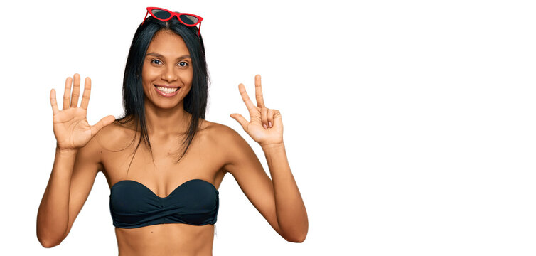 Young african american woman wearing bikini showing and pointing up with fingers number eight while smiling confident and happy.