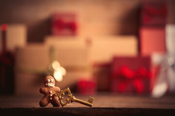 Gingerbread man and key on table with Christmas gifts on background