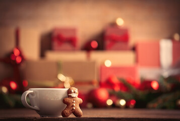 Cup of coffee with gingerbread man and Christmas gift on wooden table
