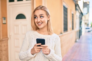 Fototapeta na wymiar Young blonde girl smiling happy using smartphone at the city.