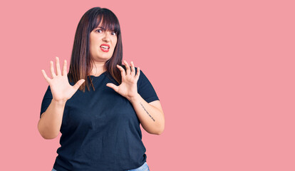 Young plus size woman wearing casual clothes afraid and terrified with fear expression stop gesture with hands, shouting in shock. panic concept.