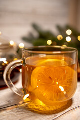 
a cup of hot Christmas tea with lemon on a light wood. against the background of an asterisk star anise, an orange and a sprig of a Christmas tree. christmas concept