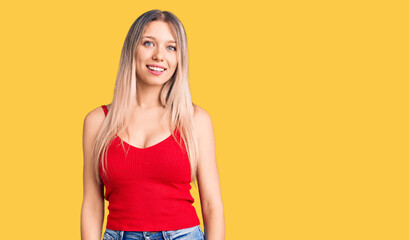 Young beautiful blonde woman wearing casual clothes looking positive and happy standing and smiling...