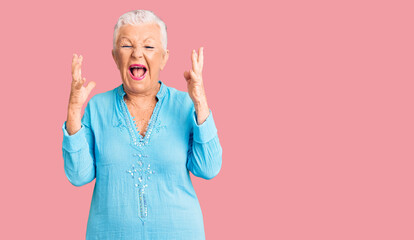 Senior beautiful woman with blue eyes and grey hair wearing summer dress celebrating mad and crazy...
