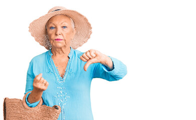 Senior beautiful woman with blue eyes and grey hair wearing fashion dress and hat holding summer...