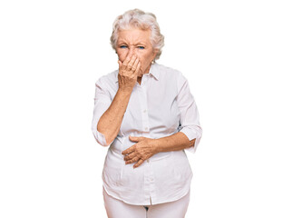 Senior grey-haired woman wearing casual clothes smelling something stinky and disgusting,...