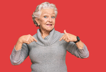 Senior grey-haired woman wearing casual winter sweater looking confident with smile on face, pointing oneself with fingers proud and happy.