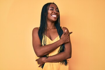African american woman with braids wearing casual clothes cheerful with a smile of face pointing with hand and finger up to the side with happy and natural expression on face