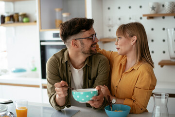 Young couple eating breakfast at home. Loving couple enjoying in the kitchen.