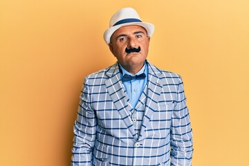 Mature middle east man with mustache wearing vintage and elegant fashion style relaxed with serious expression on face. simple and natural looking at the camera.