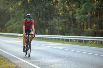 Fototapeta na wymiar Cyclist riding bike on asphalt road among nature
