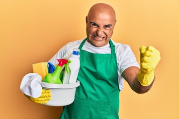 Mature middle east man wearing cleaner apron holding cleaning products annoyed and frustrated...