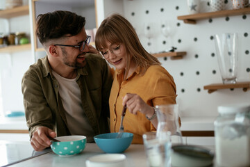 Young couple eating breakfast at home. Loving couple enjoying in the kitchen.