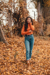 Woman in sweater walks in autumn park.