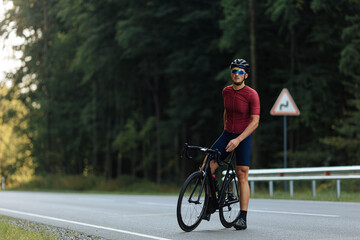 Obraz premium Young cyclist with muscular body relaxing on road