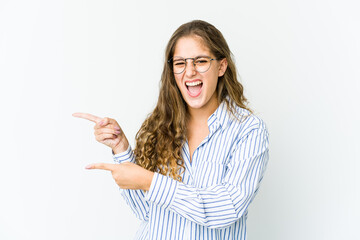 Young caucasian woman pointing with forefingers to a copy space, expressing excitement and desire.