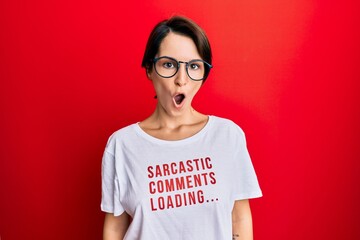 Fototapeta premium Young brunette woman with short hair wearing sarcastic comments loading t-shirt scared and amazed with open mouth for surprise, disbelief face